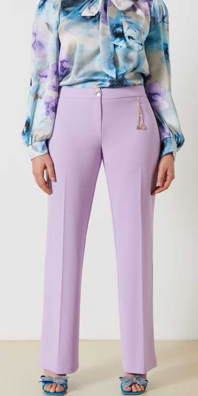 Pantalone curvy in tessuto scuba mano crepe. Questo particolare tessuto a maglia conferisce elasticità e comfort. 
Modello dritto con abbottonatura sul davanti e ciondolo gioiello removibile sul fascione. Colore viola lilla.
Il capo è interamente realizzato in Italia. La modella è alta 1,74 e indossa una taglia 46.