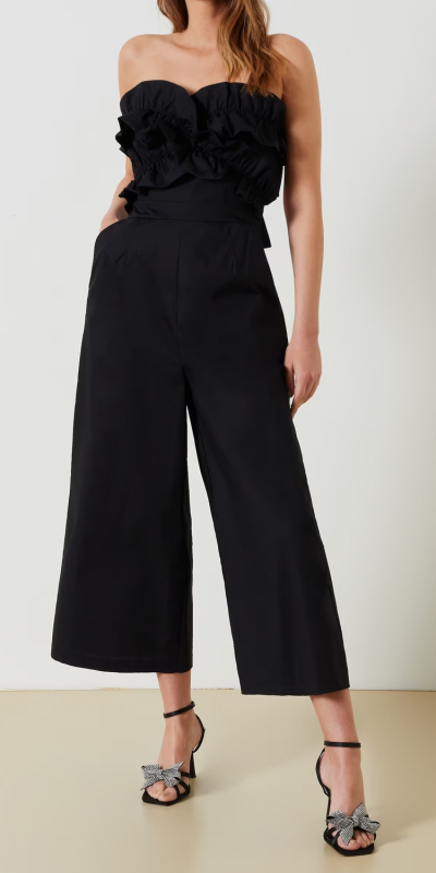 Tuta intera alla caviglia realizzata in cotone. La tuta ha il corpetto interamente decorato da rouches che valorizzano il dècolletè. 
Spalline sottolini e regolabili. Il pantalone arriva alla caviglia ed è a palazzo. Dettaglio cut-out sul retro che scopre la schiena con chiusura a fiocco.
 Zip a scomparsa posteriore al centro del pantalone. 
Capo leggero perfetto per il giorno con una slip on e per la sera con un sandalo gioiello. 
Il capo è interamente made in Italy. La modella è alta 1,77 ed indossa la taglia S.