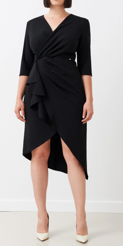 Abito tubino curvy in tessuto scuba mano crepe. Modello aderente con scollo incrociato che abbraccia il decolletè. Dettaglio di arriccio con voulant sul fianco sinistro. Lunghezza sotto al ginocchio con fondo asimmetrico. Pratica zip invisibile sul centro dietro. Maniche tre quarti. 
Il modello abbraccia perfettamente la silouette grazie all'elasticità del tessuto. Colore nero. 
Il capo è interamente made in Italy. 
La modella è alta 1,78 m e indossa una taglia 48