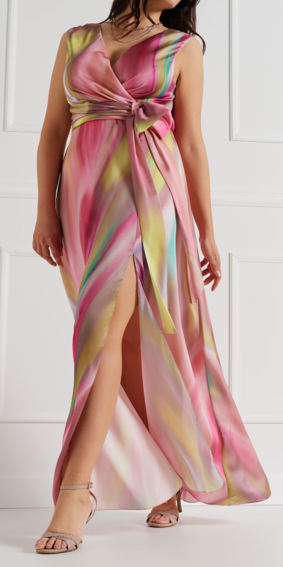 Abito curvy realizzato in raso fluido effetto sfumato multicolore. Modello con ampia gonna a ruota e profondo spacco sul davanti.
Elegante scollo incrociato che abbraccia il decolletè. 
Punto vita evidenziato da un dettaglio a fiocco sul lato. Elastico sul punto vita dietro e zip invisibile sulla schiena. 
Il capo è interamente realizzato in Italia. La modella è alta 1,78 e indossa una taglia 48.