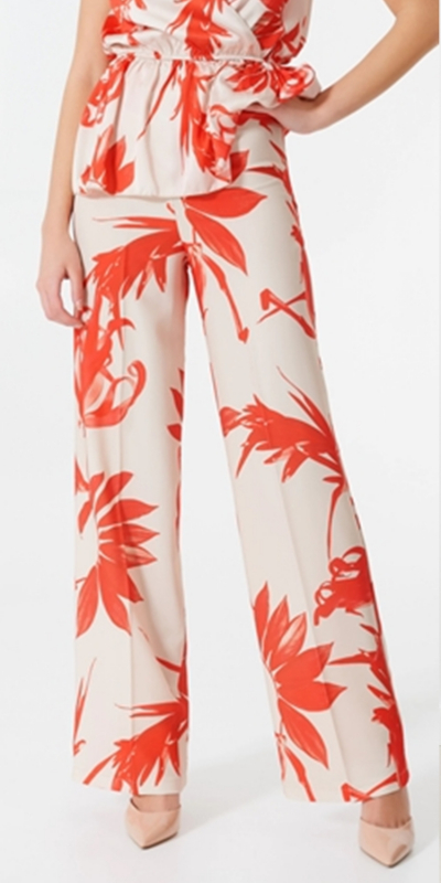 Pantaloni modello palazzo, in tessuto fluido jersey crêpe, stampa floreale nei toni del rosso. Larghezza al fondo 27 cm. I pantaloni hanno la piega frontale e sono chiusi da una zip laterale. Abbina i pantaloni alla blusa nella medesima fantasia e ad un blazer corallo. Il capo è interamente made in Italy. La modella è alta 1,75 m ed indossa la taglia S.