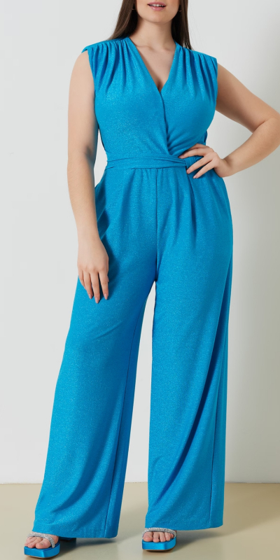 Tuta curvy in maglina lurex. Modello con scollo a V incrociato. Cinta fissa in vita con elastico sul dietro e pantalone palazzo. Perfetta anche per tutte le occasioni. Il capo è interamente realizzato in Italia. La modella è alta 1,78 e indossa una taglia 48.