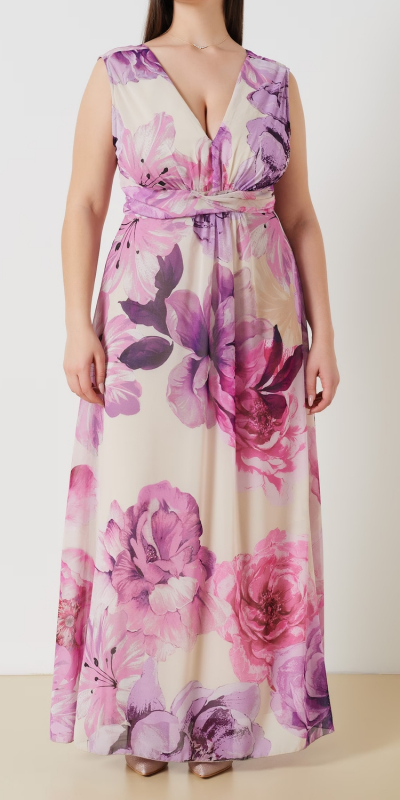 Abito lungo curvy in tessuto georgette stampa floreale. Modello stile impero con elegante scollo a V e fascione intrecciato in vita. Gonna ad A completamente foderata. Abbottonatura sul centro deitro con zip invisibile e pratico fiocco fermato in vita per regolarne la vestibilità. Colore variante lilla. Il capo è interamente realizzato in Italia. La modella è alta 1,72 e indossa una taglia 48.